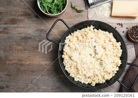 Delicious risotto with cheese on wooden table, flat lay. Space for text 109120161