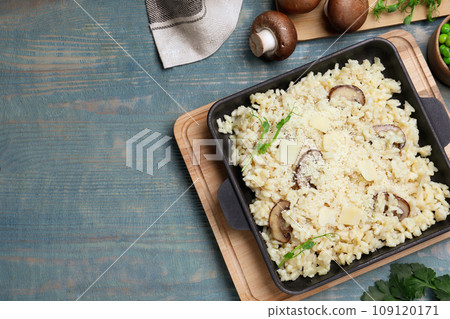 Delicious risotto with cheese and mushrooms on light blue wooden table, flat lay. Space for text 109120171