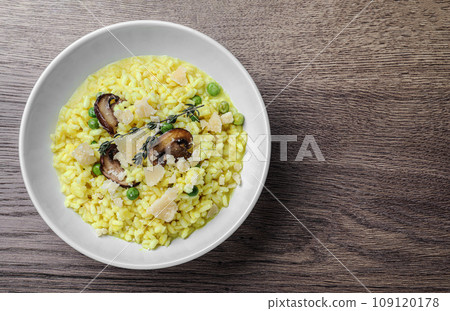 Delicious risotto with cheese and mushrooms on wooden table, top view. Space for text 109120178