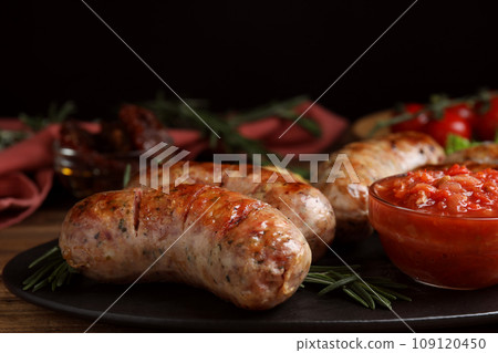 Tasty grilled sausages served with sauce on wooden table 109120450