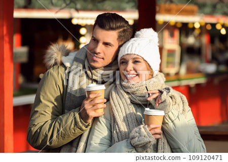 Happy couple in warm clothes with drinks at winter fair. Christmas season 109120471