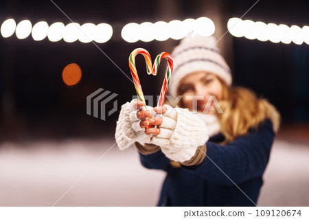 Cheerful young woman holding sparkler in hand in winter forest. Happy cute girl posing with sparkler 109120674