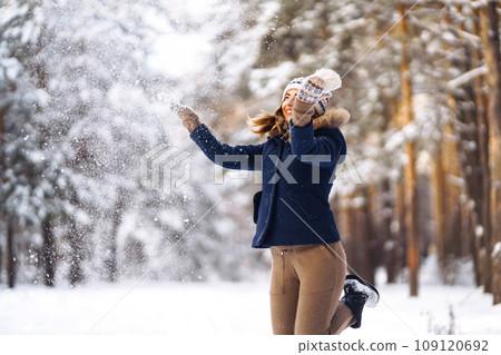 Happy young woman plays with a snow in sunny winter day. Girl enjoys winter, frosty day. Playing with snow. Happy young woman plays with a snow in sunny winter day. Girl enjoys winter, frosty day. Playing with snow. 109120692