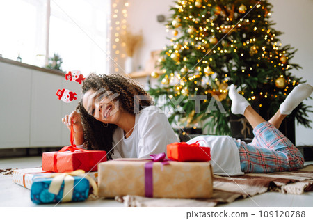 Portrait of happy woman celebrating winter holidays with large gift boxes near Christmas tree. Christmas surprise. 109120788