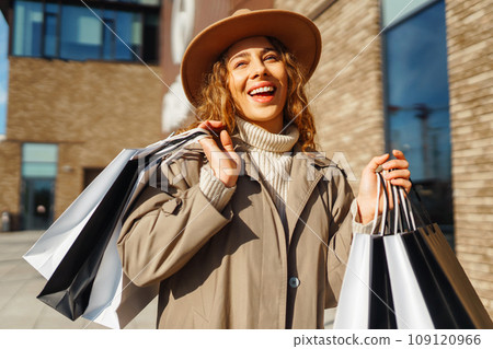 Stylish woman with shopping bags walks through city streets. Spring Style. Lifestyle concept. Stylish woman with shopping bags walks through city streets. Spring Style. Lifestyle concept. 109120966