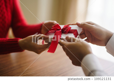 Man gives to his woman a gift box with red ribbon. Hands of man gives surprise gift box for girl. Man gives to his woman a gift box with red ribbon. Hands of man gives surprise gift box for girl. 109121131