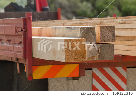 Close-up of wooden planks bars immersed in car trailer. Wood Industry, Transportation board Close-up of wooden planks bars immersed in car trailer. Wood Industry, Transportation board 109121319