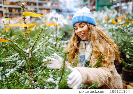 Beautiful young woman buys a Christmas tree at the fair. New Year's holiday concept 109121594