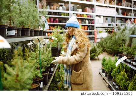 Beautiful young woman buys a Christmas tree at the fair. New Year's holiday concept 109121595
