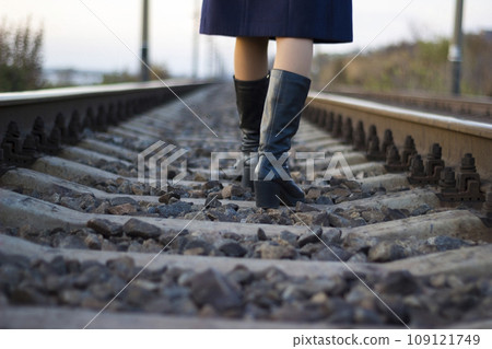 Girl walks on railway rails in a coat and boots - travel, lifestyle Girl walks on railway rails in a coat and boots - travel, lifestyle 109121749