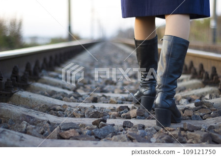 Girl walks on railway rails in a coat and boots - travel, lifestyle Girl walks on railway rails in a coat and boots - travel, lifestyle 109121750