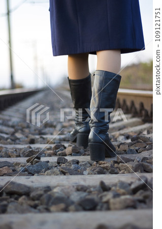 Girl walks on railway rails in a coat and boots - travel, lifestyle Girl walks on railway rails in a coat and boots - travel, lifestyle 109121751