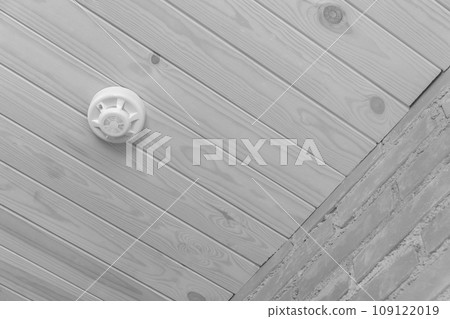 Fire alarm on wooden ceiling in grey interior smoke detector safety and home protection from dangerous with fire, close-up Fire alarm on wooden ceiling in grey interior smoke detector safety and home protection from dangerous with fire, close-up 109122019