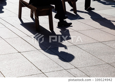 Silhouette of a person sitting on a bench in the square 109124942
