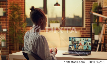 African american adult on videocall doing briefing session for updates and new research plan to solve tasks. Woman waving at online videoconference meeting, using laptop and webcam. African american adult on videocall doing briefing session for updates and new research plan to solve tasks. Woman waving at online videoconference meeting, using laptop and webcam. 109126245
