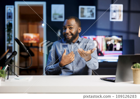 African american content creator doing travelling recommendations type of video for fans, filming in his apartment. Online show host sharing with viewers his favorite cities 109126283