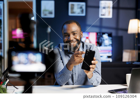 Internet show host being sponsored by partnering brand to do cellphone unboxing content. Technology enthusiast does influencer marketing, doing mobile phone product commercial Internet show host being sponsored by partnering brand to do cellphone unboxing content. Technology enthusiast does influencer marketing, doing mobile phone product commercial 109126304