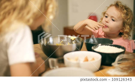 Two cute little girls cook a cake together at home 109126343