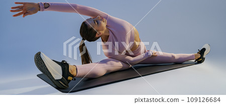 Flexible woman doing stretching exercises on yoga mat on studio background. Healthy lifestyle 109126684