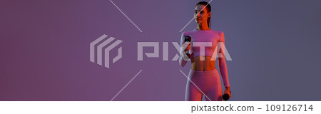 Attractive fitness woman doing exercises with dumbbells on studio background with colored filter Attractive fitness woman doing exercises with dumbbells on studio background with colored filter 109126714