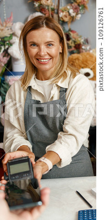 Customer paying for order in a flower shop using her smartphone 109126761