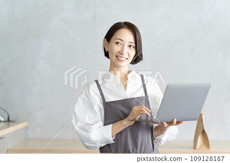 A woman in an apron with a laptop 109128187