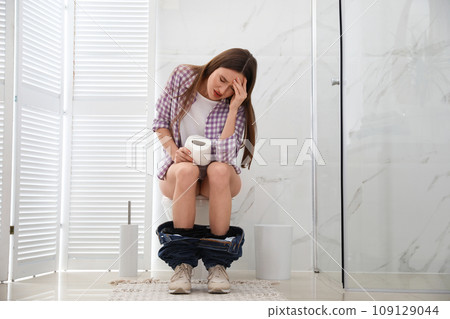 Woman with paper suffering from hemorrhoid on toilet bowl in rest room Woman with paper suffering from hemorrhoid on toilet bowl in rest room 109129044