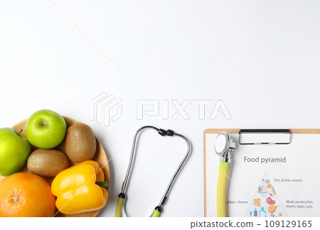 Fruits, vegetables, stethoscope and list of products on white background, top view. 109129165