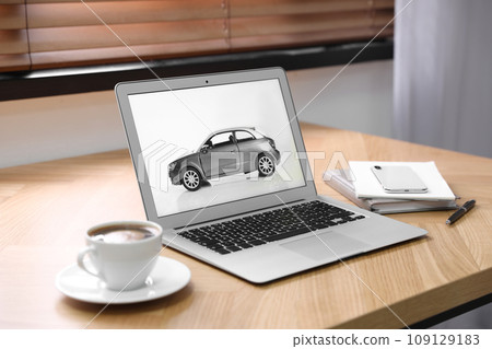 Laptop screen with automobile on wooden table. Car buying` Laptop screen with automobile on wooden table. Car buying` 109129183
