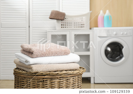 Fresh towels on wicker basket in laundry room 109129339