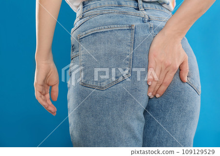 Woman suffering from hemorrhoid on light blue background, closeup 109129529