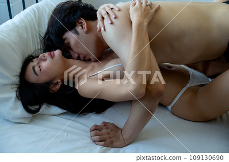 Asian man kiss on crook of the neck of woman who lie down on bed look like they enjoy sexual activity at home. Asian man kiss on crook of the neck of woman who lie down on bed look like they enjoy sexual activity at home. 109130690