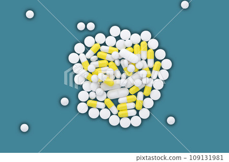 A pile of white and yellow pills lie on a blue background. A pile of white and yellow pills lie on a blue background. 109131981