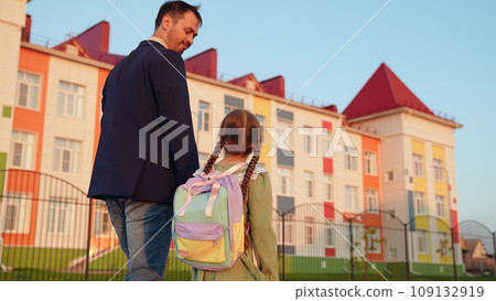 father leads his daughter hand school. happy life family. little child daughter holds happy father hand while going school house. little child and his parent go to class. school life kid with bag his father leads his daughter hand school. happy life family. little child daughter holds happy father hand while going school house. little child and his parent go to class. school life kid with bag his 109132919