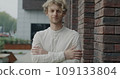 Slow motion portrait of confident person standing in city street next to office building smiling looking at camera. Modern youth and positive emotion concept. 109133804
