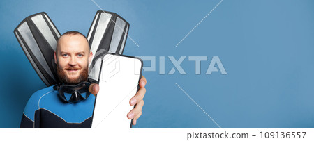Happy diver diving man with flippers holding smartphone with empty white screen display 109136557