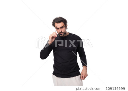 a well-groomed young caucasian man with black hair and a beard took off his glasses for vision and 109136699