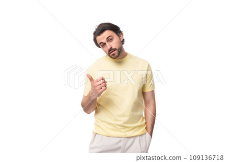 young brutal brunette man in a T-shirt points his hand to the side on a white background with copy 109136718