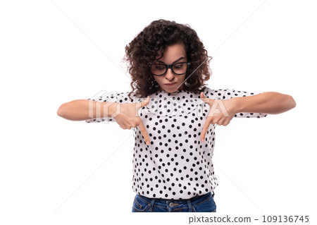 a young woman with a curly hairstyle dressed in a summer blouse with a polka dot print shows her 109136745