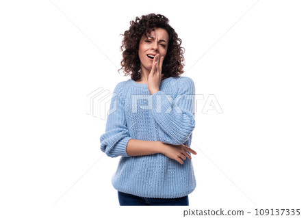 portrait of a charming young caucasian woman with curly dark hair dressed in a casual warm blue 109137335