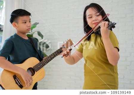 Asian boy playing guitar and mother playing violin, feel appreciated and encouraged. Concept of a happy family, learning and fun lifestyle, love family ties 109139149