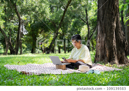 Happy Asian senior woman using laptop for working online outside office. Elderly retirement using laptop for learning new skill and freelance working in park, senior lifestyle with technology Happy Asian senior woman using laptop for working online outside office. Elderly retirement using laptop for learning new skill and freelance working in park, senior lifestyle with technology 109139383