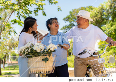 Happy and healthy Asian family standing beside a bicycle after workout together. friendship lifestyle, Enjoyment of active seniors, outdoor activity after retirement, health care insurance concept. Happy and healthy Asian family standing beside a bicycle after workout together. friendship lifestyle, Enjoyment of active seniors, outdoor activity after retirement, health care insurance concept. 109139394