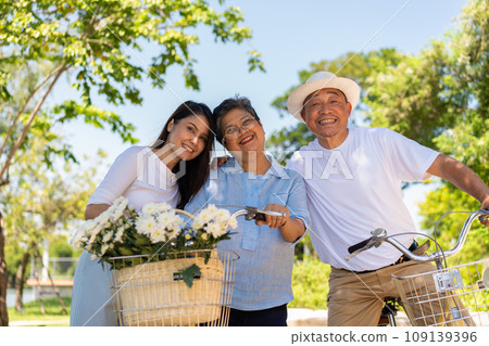 Happy and healthy Asian family standing beside a bicycle after workout together. friendship lifestyle, Enjoyment of active seniors, outdoor activity after retirement, health care insurance concept. Happy and healthy Asian family standing beside a bicycle after workout together. friendship lifestyle, Enjoyment of active seniors, outdoor activity after retirement, health care insurance concept. 109139396
