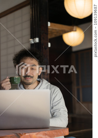 A man working on a computer in an old house. Remote work and life in the countryside. A man working on a computer in an old house. Remote work and life in the countryside. 109139687