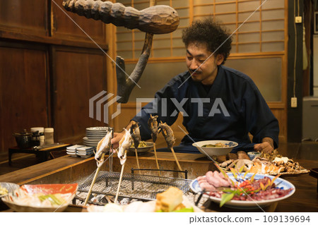 A bearded Japanese man enjoying a meal while staying at a travel inn. A bearded Japanese man enjoying a meal while staying at a travel inn. 109139694