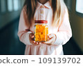 Schoolgirl child holds in her hands a jar of chewable gummy vitamins. The concept of taking vitamins to keep the child healthy while studying 109139702