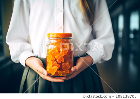 Schoolgirl child holds in her hands a jar of chewable gummy vitamins. The concept of taking vitamins to keep the child healthy while studying Schoolgirl child holds in her hands a jar of chewable gummy vitamins. The concept of taking vitamins to keep the child healthy while studying 109139703