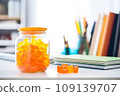 A jar of Gummy Vitamins is on the student's desk. The concept of taking vitamins to maintain child health while studying 109139707