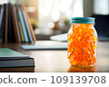 A jar of Gummy Vitamins is on the student's desk. The concept of taking vitamins to maintain child health while studying 109139708